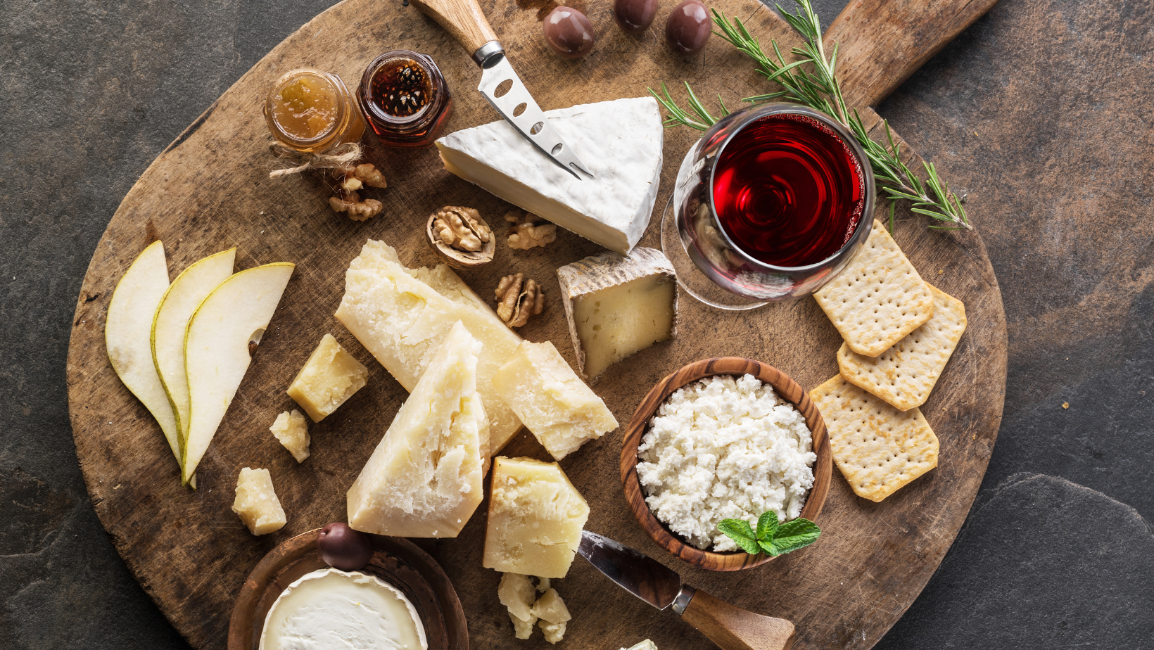 Cheese plate with assorted cheeses and a glass of red wine on a rustic table